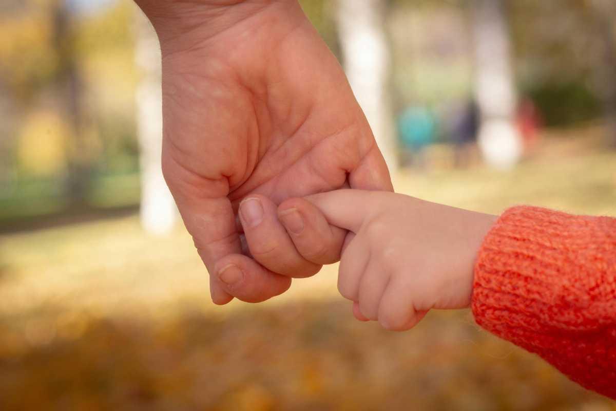 La mano di un adulto che stringe la mano di un bambino