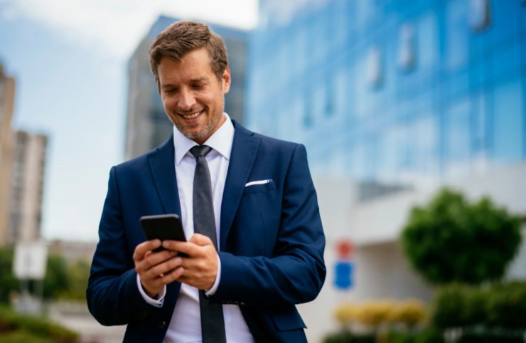 uomo che sorride mentre guarda il cellulare