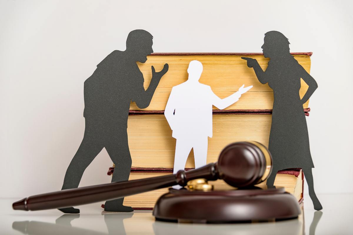 coppia che litiga con giudice sullo sfondo e martelletto giudice in primo piano