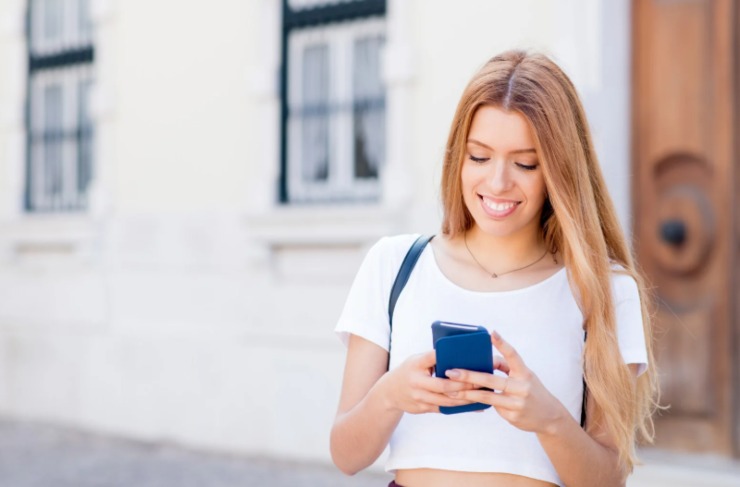 ragazza sorridente che chatta con il cellulare in mano