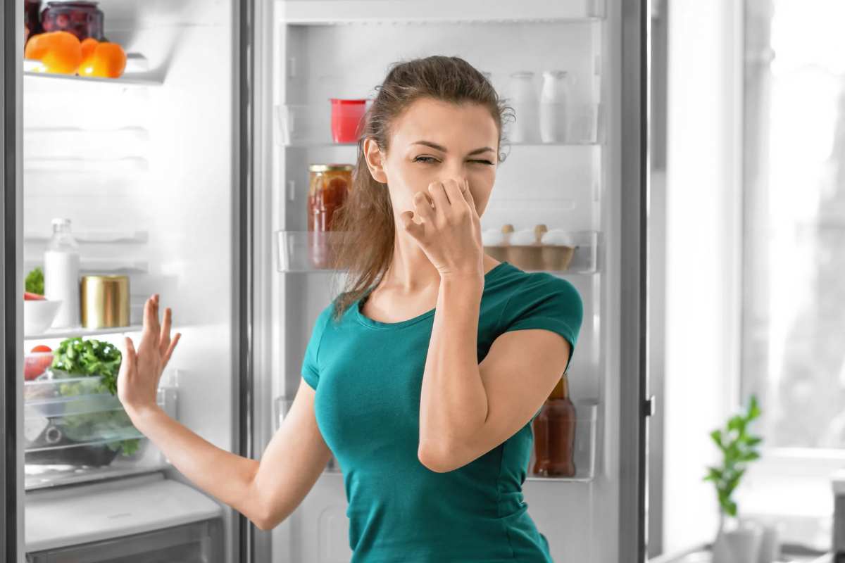 Donna che si copre il naso dopo aver aperto il frigorifero